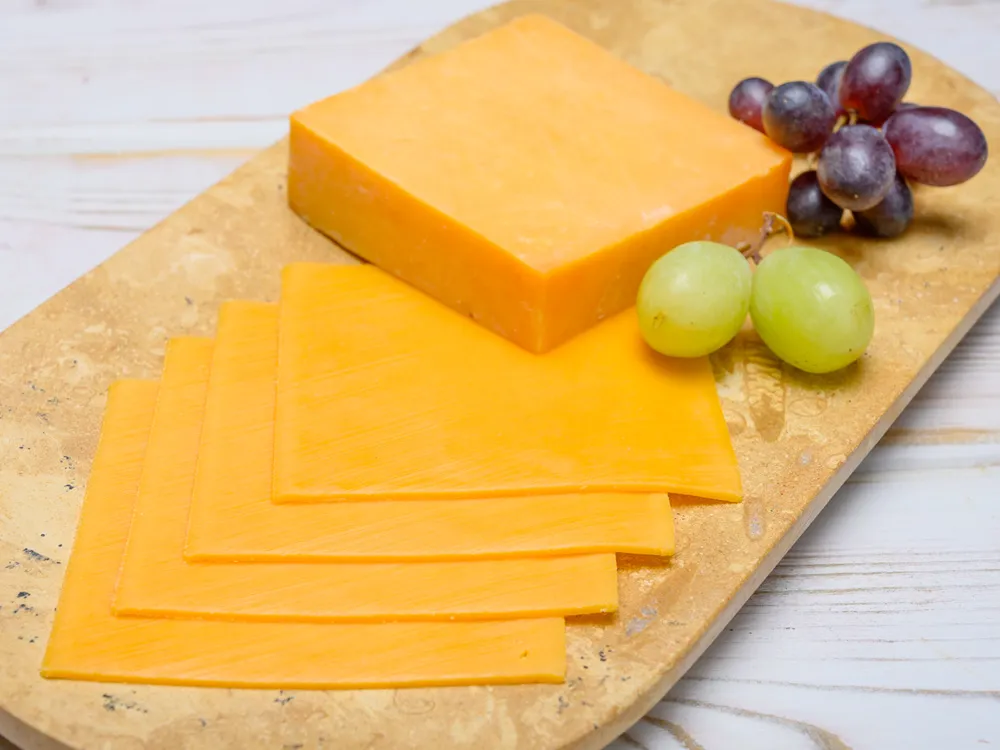 Blocks and slices of yellow American cheese arranged on a wooden cutting board